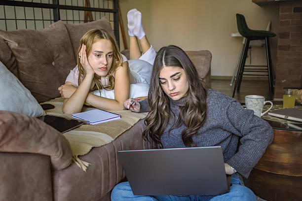 istock Concentrated young women university students learning together for exams at home. Digital nomad roommates working from cozy apartment. 2220735093