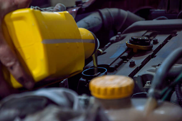 istock A person is pouring engine oil into the car engine during routine service, ensuring the vehicle runs smoothly and efficiently 2220737148