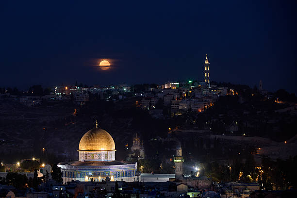 A full moon rises low on the horizon over Mount Scopus and the Old City of Jerusalem, Israel. stock photo