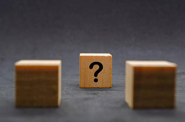 Two dark wooden cubes with question marks on a black background.