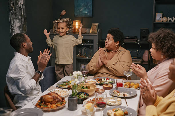 istock Black Boy Playing at Dinner Table Entertaining Family during Celebration 2220740281