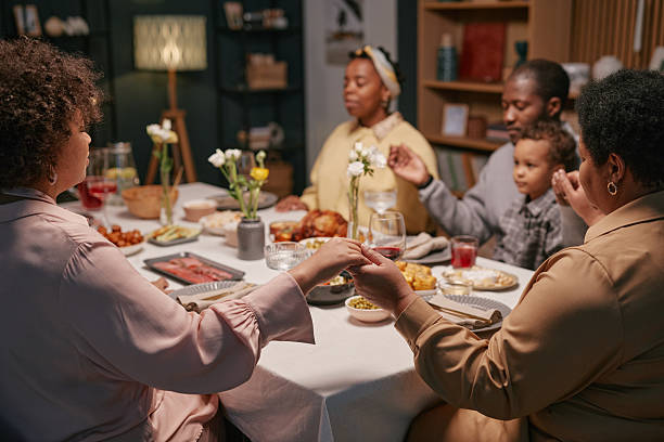 istock Black Family Holding Hands Praying before Festive Dinner at Home 2220740323