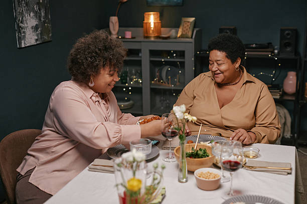 istock Young and Elderly Black Women Sharing Meal at Festive Home Dinner 2220740326