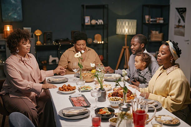 istock Black Family Praying before Meal in Cozy Dining Room 2220740334