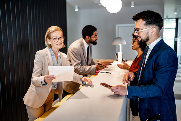 istock Hotel receptionist handing over documents to businesspeople 2220741203