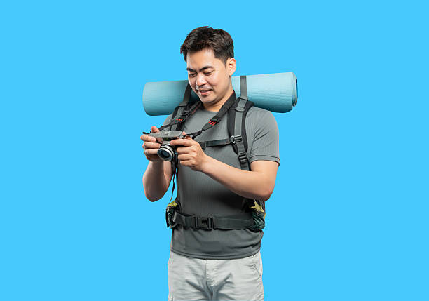 istock Hiker pauses to check photos on his camera during a backpacking trip with a blue background 2220746782