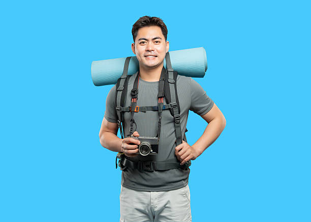 istock Smiling backpacker with camera ready for adventure isolated on a bright blue background 2220746806