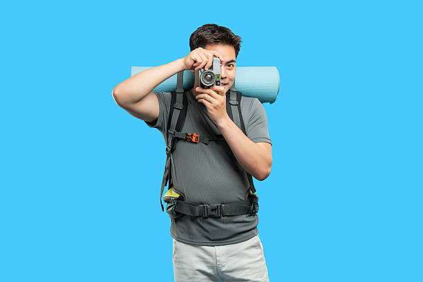 Adventurous photographer with backpack captures memories on vacation; bright background vibrant