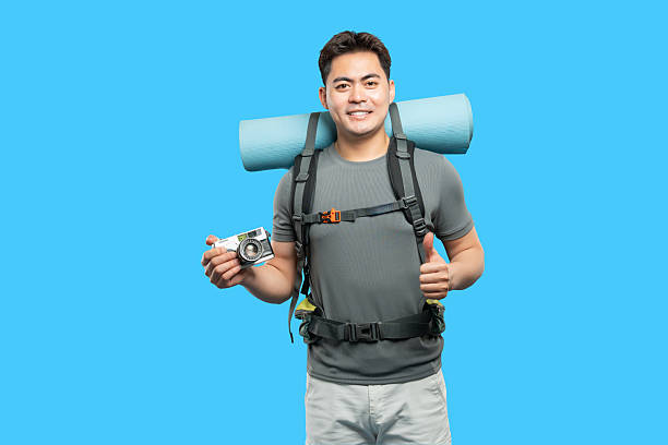 istock A cheerful hiker with a camera and backpack gives a thumbs-up on a bright blue background 2220746845