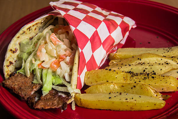 istock A mouthwatering wrap filled with fresh vegetables and delicious meat, served alongside a portion of golden fries on a vibrant plate for a complete meal experience. 2220748897