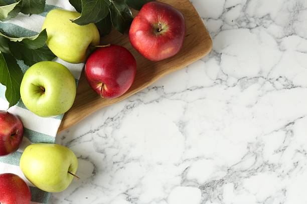 istock Ripe apples and green leaves on white marble table, top view. Space for text 2220751617