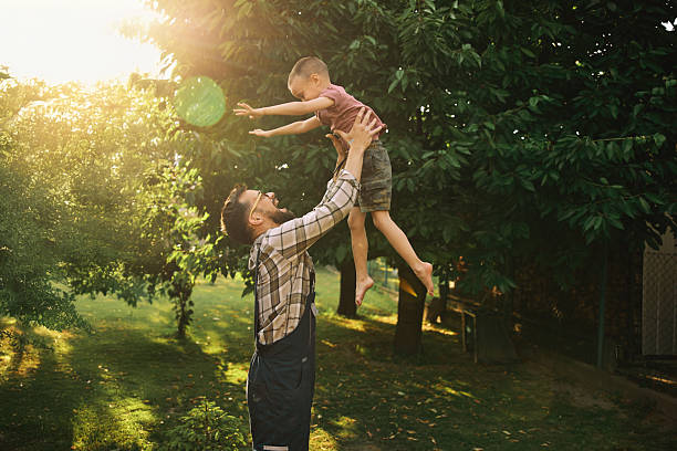 istock Playful father is tossing his son in the air in backyard. 2220751668