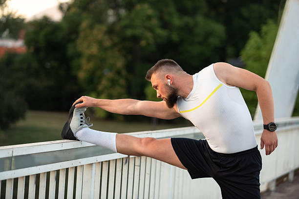 istock A young athletic man is doing stretching exercises before running or workout on a city bridge, Outdoor fitness preparation, active lifestyle concept. 2220752829