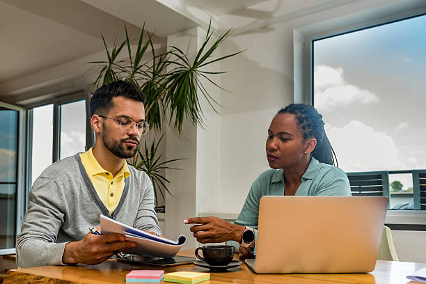 istock Two business professionals working together in an office reviewing documents and analyzing ideas using a laptop during a collaborative meeting focused on planning, development, and strategic execution 2220754796