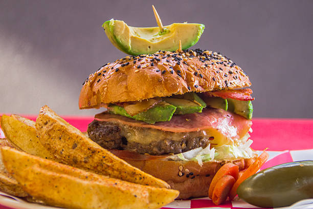 Delicious grilled salmon burger with melted cheese, tomatoes and lettuce on a bun, served with French fries.