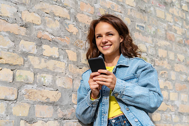 istock Young urban woman using smartphone near the brick wall 2220754855