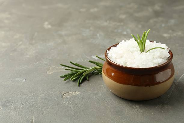 istock Sea salt in bowl and rosemary on grey table, closeup. Space for text 2220757629