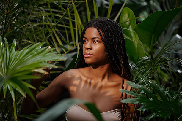 Woman with long hair gently touching lush green leaves in tropical jungle. Capturing tranquil moment surrounded by natural beauty and vibrant greenery