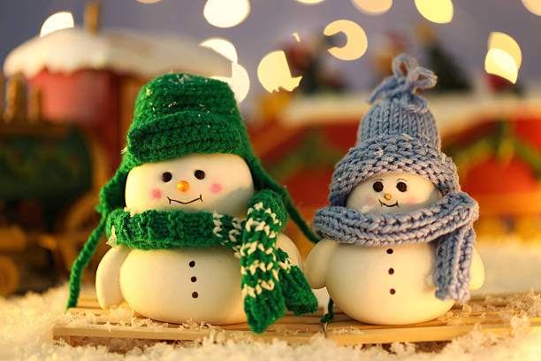 Cute decorative snowmen on artificial snow against blurred background, closeup