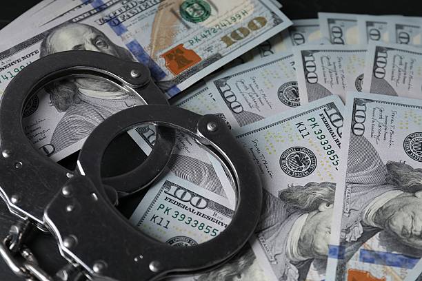 istock Corruption. Handcuffs and dollar banknotes on table, closeup 2220759199