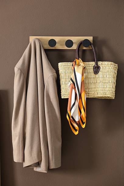 istock Coat rack with wicker bag and jacket on brown wall in hallway 2220759578