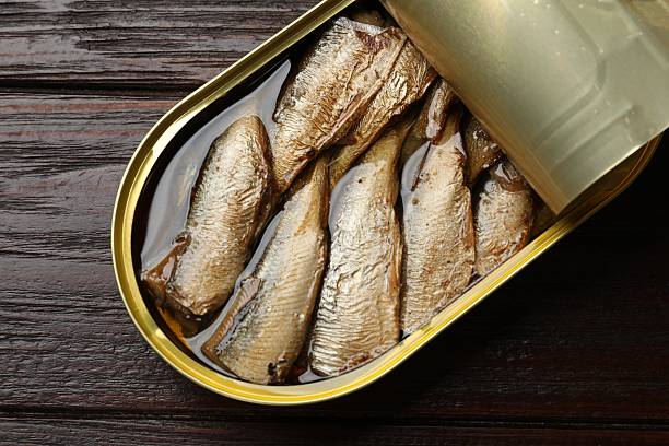 istock Tasty sprats in tin can on wooden table, top view 2220762621