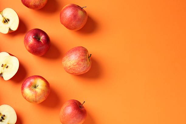istock Whole and cut fresh red apples on orange background, flat lay. Space for text 2220763042