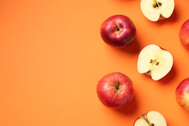 istock Whole and cut fresh red apples on orange background, flat lay. Space for text 2220763058