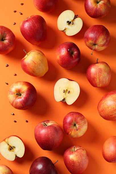 istock Fresh red apples and seeds on orange background, flat lay 2220763078