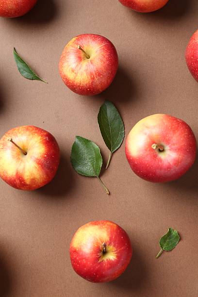 istock Ripe red apples and green leaves on brown background, flat lay 2220763081