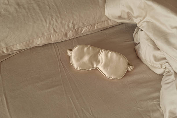 istock Silk sleep mask on a cozy beige bed. 2220763641