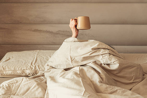 istock A hand holding a coffee mug emerging from a cozy bed. 2220763645