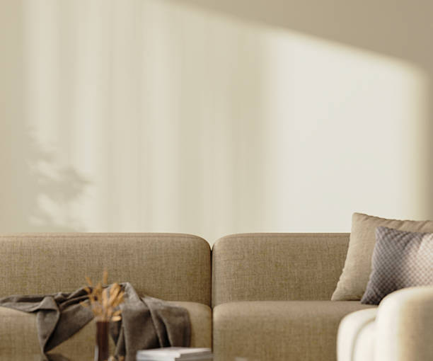 istock Empty beige wall mock-up with sunlight above brown sofa with pillows and decor, 3d render 2220764268