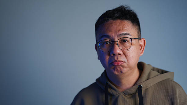 A studio video portrait of an Asian man acting as if he is uncertain and confused about something.