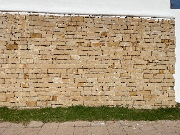 This close-up image showcases a textured stone wall, with layers of flat stones stacked tightly together. The rough surface of the stones contrasts with the subtle gaps between them, giving a natural, rustic appearance. The lighting highlights the details of the stone's surface, making this image ideal for showcasing architectural materials, stone structures, or environmental textures.