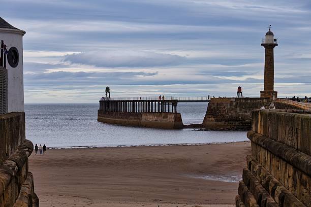 istock A beach scene featuring a sandy shore, a pier with a lighthouse, and a ship-like structure in the water 2220778711