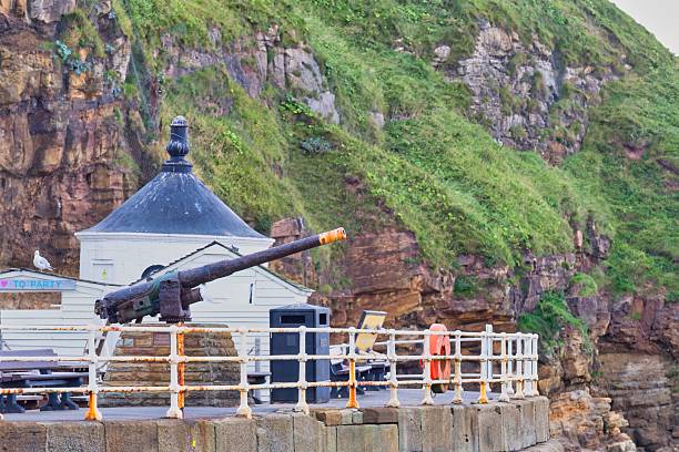 istock A quaint white lighthouse sits on a pier with a cannon pointed seaward, 2220778745