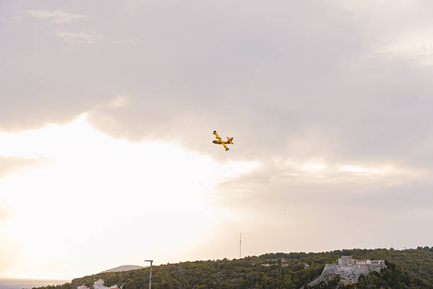 A yellow Canadair firefighting airplane soars across a blue sky over Croatia during wildfire season. The high-contrast sky highlights the aircraft’s distinct shape and mission – combating fires in remote, mountainous terrain. This image is perfect for editorial use, civil defense features, and environmental awareness campaigns.