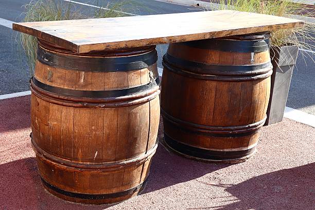istock Two rustic wooden barrels with black metal bands support a thick wooden tabletop 2220791255