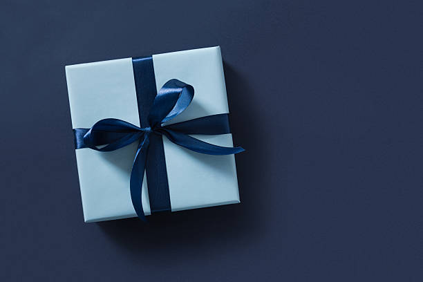 Blue gift box on navy blue background. View from above.