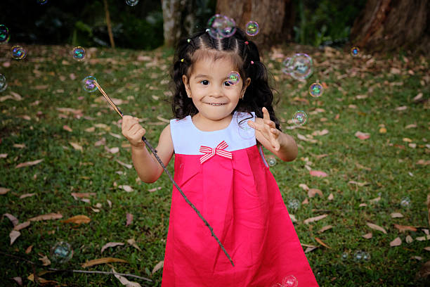 Preschool girl playing joyfully with soap bubbles in a park, enjoying a sunny day filled with laughter and carefree moments