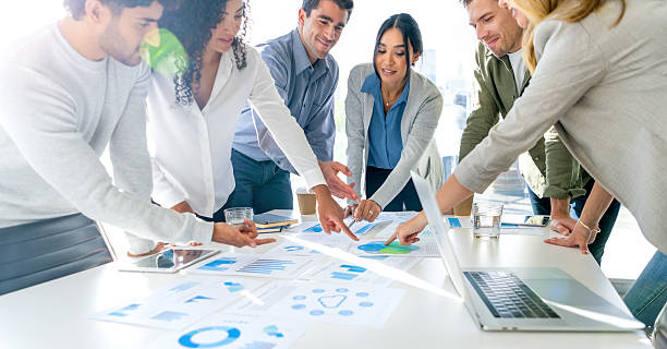 istock Financial and business documents on table with multiethnic group of people working on them. 2220803224
