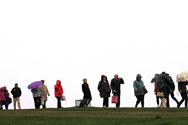 A long curve of tourists walks across a hill in Ireland, umbrellas breaking the monotony of the white sky. Their quiet procession captures the texture of everyday travel in wet weather.