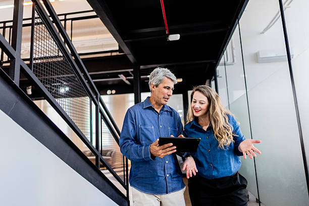 istock Coworkers using laptop and walking in the office corridor 2220807357