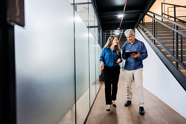 istock Coworkers using laptop and walking in the office corridor 2220807361