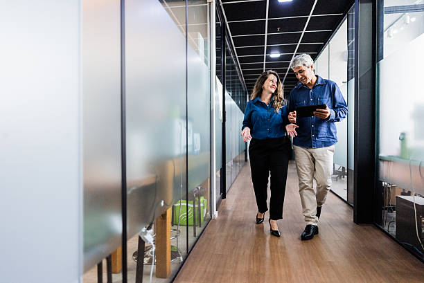 istock Coworkers using laptop and walking in the office corridor 2220807378