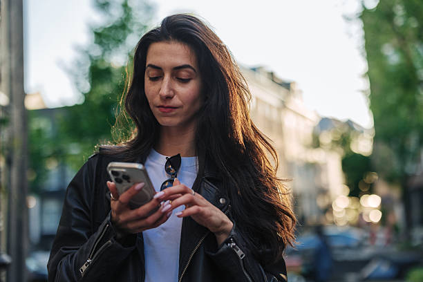 istock Young woman using smartphone while walking in the city 2220812617