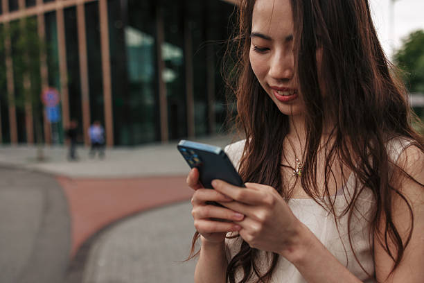 istock Young Woman Using Smartphone on City Street 2220812650