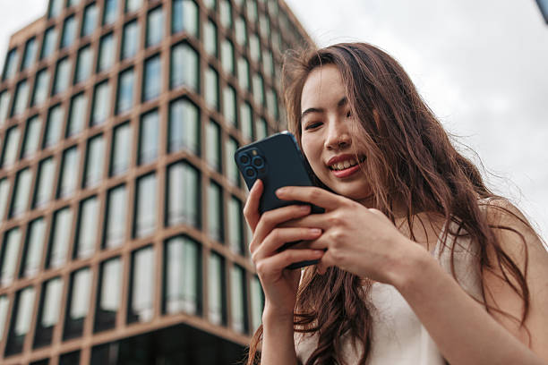 istock Young woman using smartphone in front of modern building 2220812655