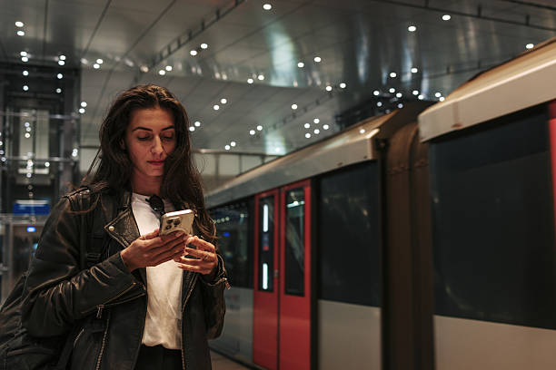 istock Young woman using smartphone while waiting for train in subway station 2220812663